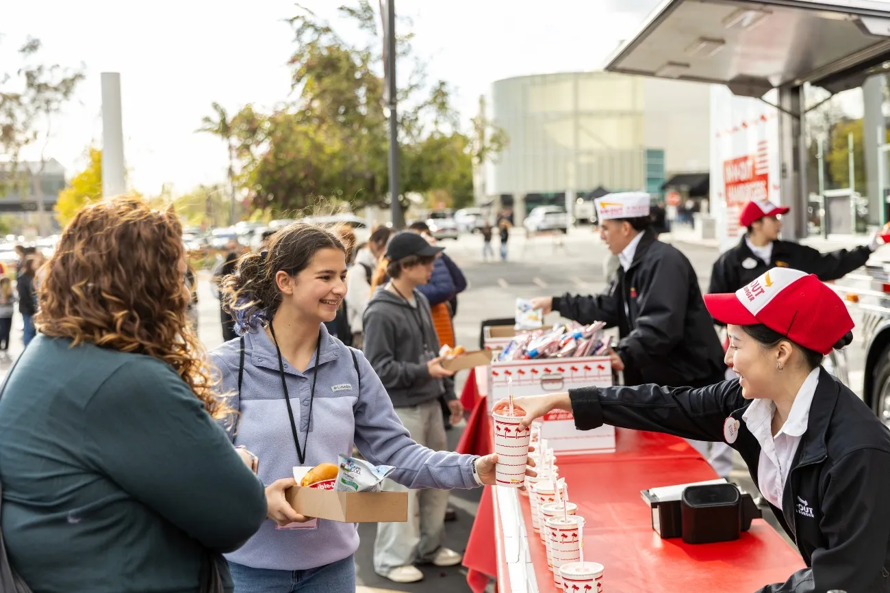 student smiling while grabing a in and out burger